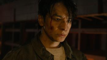 Demon City movie: Japanese man in dark room center looks menacing with bloodied and dirtied face