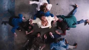 Dicks: The Musical Movie: Megan Thee Stallion sings to a camera above her while wearing a power suit in the middle of some wiped-out men