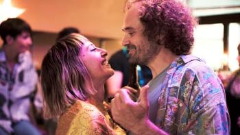 A couple smiling and dancing in a festive atmosphere.