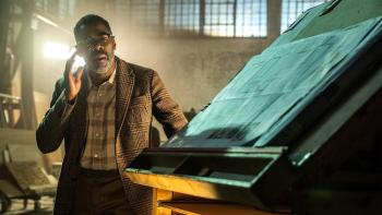Disclosure Day Movie: Hugo (Colman Domingo) stands next to blueprints on a drafting table and touches a com near his ear