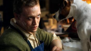 DogMan Movie: Douglas (Caleb Landry Jones), white smudges on his face, looks a dog in the eyes, as if pondering something