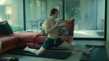 Don't Die: The Man Who Wants to Live Forever movie: White middle-aged shirtless man in shorts stretches in living room with a bowl of food in hands