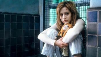 Don't Say a Word movie: A disheveled Elizabeth sits clutching her knees holding a rag doll on the sill of a barred window.