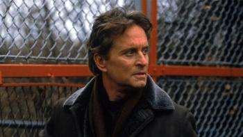 Don't Say a Word movie: Michael Douglas stands in front of a chain-link fence looking worriedly to the right.