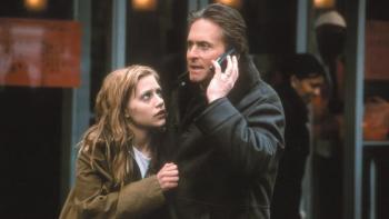 Don't Say a Word movie: Nathan talks on a cell phone while Elizabeth clutches his jacket and looks up at him worriedly.