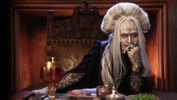 Dracula: Caleb Landry Jones is wrinkled and aging as he sits at the end of a grand dinner table