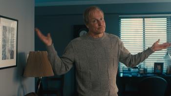 Ella McCay movie: Woody Harrelson wears a sweater in a house while holding his hands up in a shrug