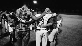 Emanuel Movie: Three men bow their heads in grief on a football field