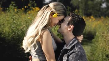 Escaping Ohio: A young couple embrace while smiling and touching foreheads in front of a field of yellow wildflowers