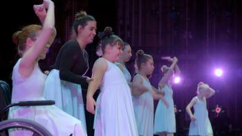 A row of dancers on stage are ready to take a bow.