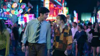 Everybody Loves Me When I'm Dead Movie: Asian man and woman walk outside in busy marketplace at night