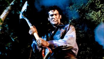 Evil Dead II Movie: In the forest, Ash looks down at something, holding up a shovel as if ready to strike