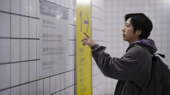 Exit 8 Movie: In a subway station, a lost man reads an information placard on the wall, tracing the lines with his finger