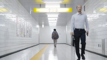 Exit 8 Movie: The lost man walks to the end of a hallway while the walking man moves toward the camera