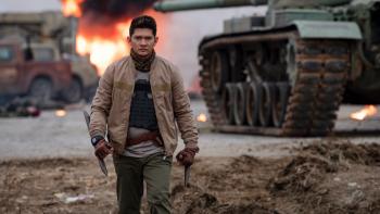 Expend4bles Movie: Villain Rahmat (Iko Uwais) walks through a battle scene, holding two bladed weapons