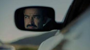 Facing El Chapo movie: Man's reflection in car side mirror against blurred landscape.