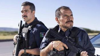 Facing El Chapo movie: Two police officers with rifles stand outdoors under a clear sky.