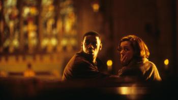 Fallen: Denzel Washington and Embeth Davidtz look over their shoulders in concern as they sit in a candlelit church pew