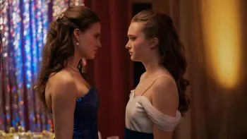 Fear Street: Prom Queen movie: White brown-haired teen girl in blue dress left faces White brown-haired teen girl in white dress right at their prom