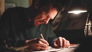 The Thing with Feathers: Benedict Cumberbatch leans over a table with a small lamp, drawing with darkness around him