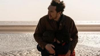 The Thing with Feathers: Benedict Cumberbatch leans down to hug his character’s two sons on the beach, with the sea behind them
