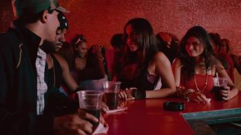 Rosa Arredondo and Melonie Diaz stand in a red-lit bar, talking with Omarion and Victor Rasuk.