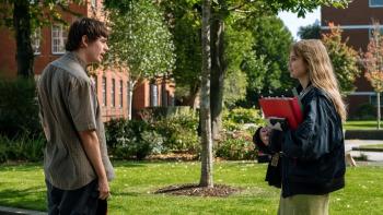 Finding Emily: A young man and woman talking outside near a brick building and trees