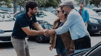 Flywheel: Ignition of the Soul: Mario Bergeira shakes hands with a man at a used car dealership