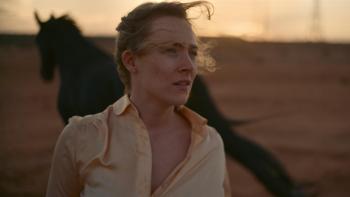 Foe: Saoirse Ronan as Hen outside in a field with a black horse behind her.