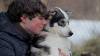 Folktales Movie: Young person hugging a dog outdoors, both looking calm.