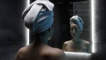 Forever Young Movie: Woman with towel on head, looking at reflection in dimly lit bathroom mirror.