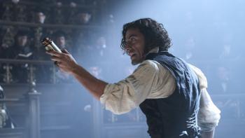 Frankenstein Movie: Holding a battery and gesturing at a crowd of scholars, Victor (Oscar Isaac) gives a furious lecture