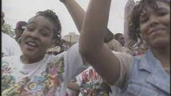 Freaknik scene 1: 2 Black young people smile and eave their hands in a crowd