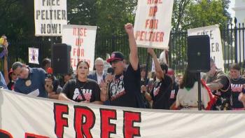 Free Leonard Peltier Movie: Protesters hold signs and a banner outdoors.