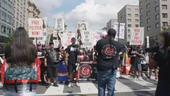 Free Leonard Peltier Movie: Crowd of activists marching with signs on a city street.
