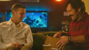 Friendship movie: Craig and Austin sit together looking into a cardboard box; a fish tank is behind Craig