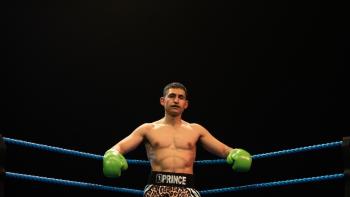 Giant: Boxer with green gloves in a ring, wearing leopard-print shorts, under spotlight