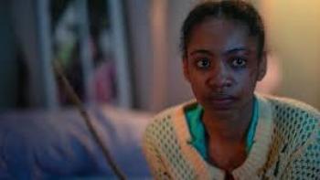 Girl in the Video movie: Young Black woman looking serious, sitting in a dimly lit room.