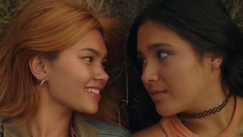 Girls Like Girls movie: Two young women lie on grass, smiling and gazing at each other tenderly
