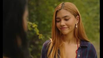 Girls Like Girls movie: A woman with long hair smiles outdoors, with blurred greenery in the background.