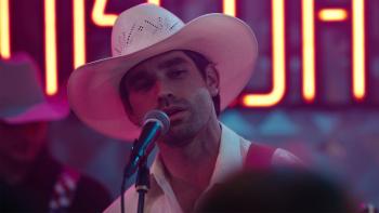 God's Country Song: A male country musician sings into a microphone in God's Country Song