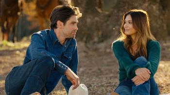 God's Country Song: A man and a woman sit outside in a field looking longingly at eachother