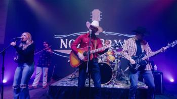 God's Country Song: A male country musician sings on stage holding a guitar