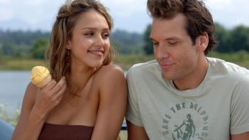 Dane Cook has his arm around Jessica Alba with a lake and forrest in the background.