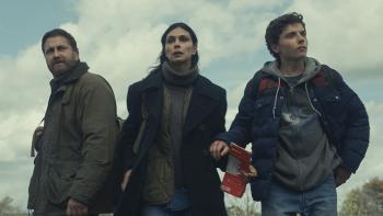 Greenland 2: Migration Movie: Weary-looking John, Allison, and Nathan Garrity are on foot, Nathan holding a map