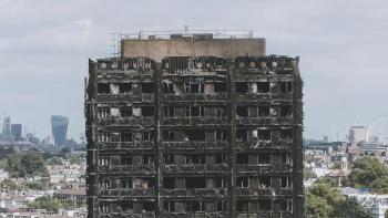 Grenfell—Uncovered: The top few floors of the burned Grenfell Tower are shown against a city backdrop