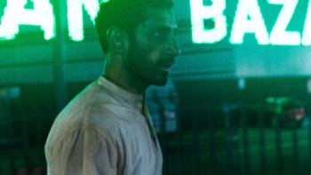 Hamlet: Riz Ahmed walks through the streets of London, which are lit by green neon signs