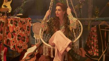 Hamlet: Alis Wyn Davies sits in a hanging chair in a brightly patterned room, a guitar next to her on the floor