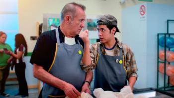 Have a Nice Day: In grocery store, Mexican man employee left stands next to Mexican teenage boy employee on right as they bag groceries
