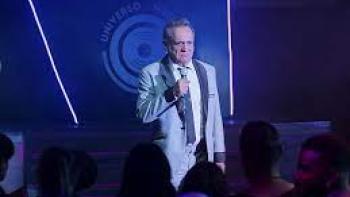 Have a Nice Day: Mexican man in white suit stands with microphone in front of a crowd at nightclub